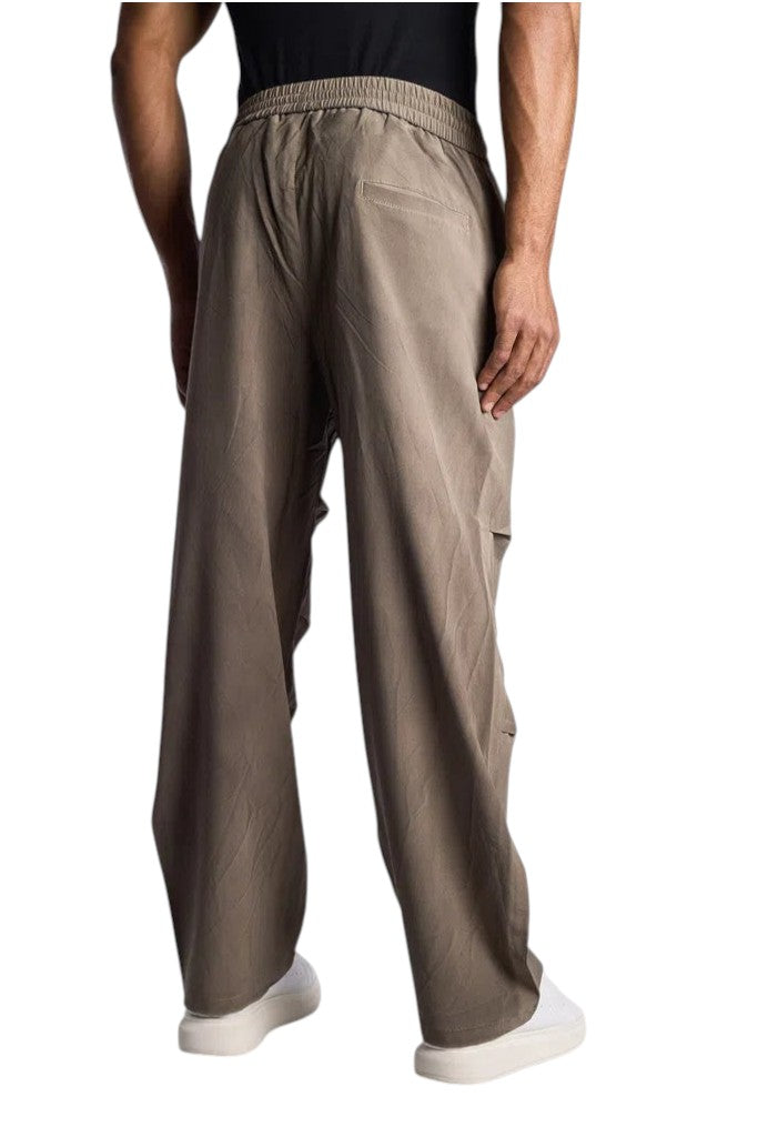Back view of a man wearing My Store ALO track pants in a relaxed taupe fit with an elastic waistband