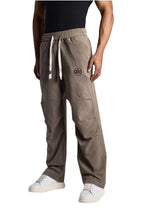 My Store ALO track pants in taupe with an elastic drawstring waist and logo detail worn by a man in white sneakers