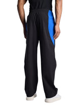 Back view of My Store BALENCIAGA black tracksuit pants with blue side panel detailing worn by a male model