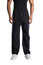 My Store BALENCIAGA black nylon tracksuit pants with blue logo detail and drawstring waist worn by a male model
