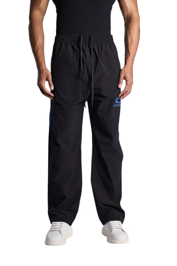 My Store BALENCIAGA black nylon tracksuit pants with blue logo detail and drawstring waist worn by a male model