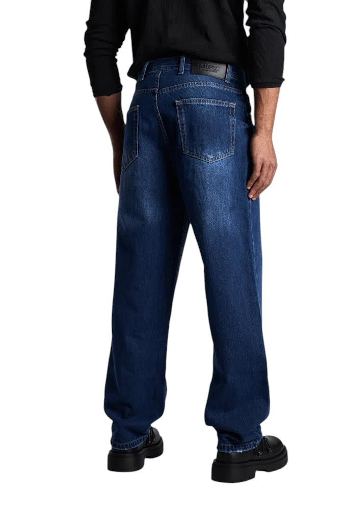 Back view of My Store dark blue baggy fit denim jeans worn by a man with black shoes