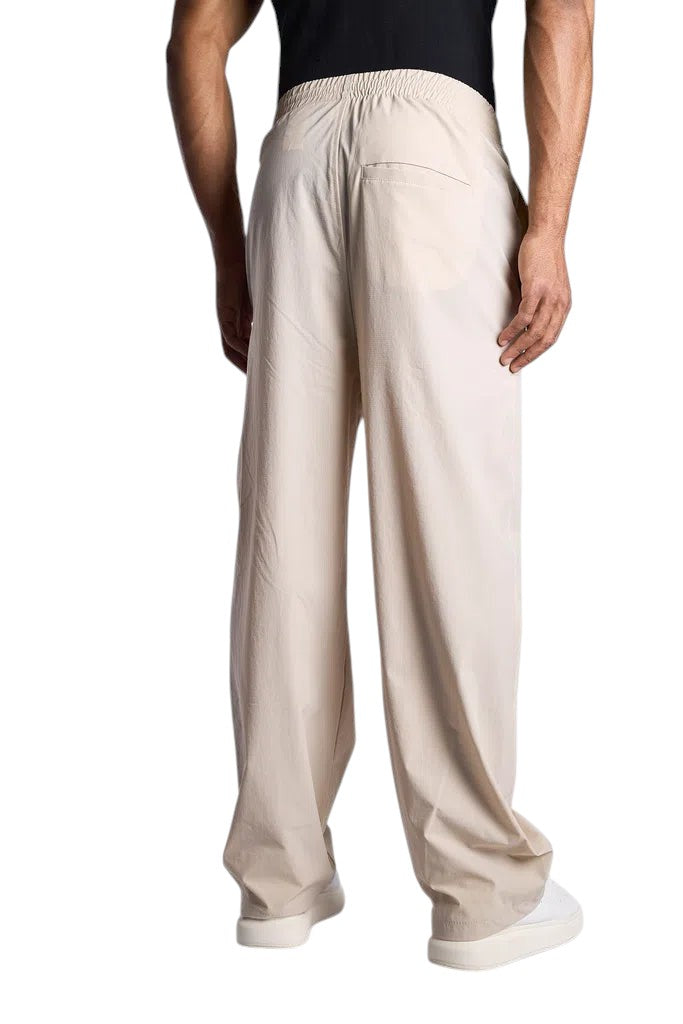 Back view of My Store ESSENTIALS track pants in beige, featuring a relaxed fit and elastic waistband.