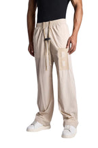 My Store ESSENTIALS beige track pants with an elastic drawstring waist and a textured patch detail on the leg