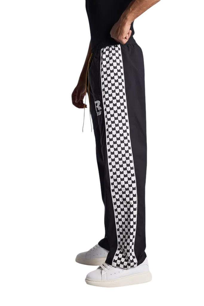 My Store Rhude black track pants with white checkered side stripe worn by a model with white sneakers