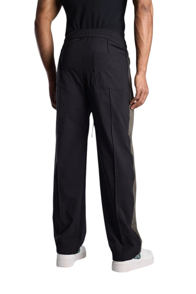 My Store Rhude black and green Aerial track pants worn by a man, back view showing straight leg fit and pocket detail.