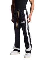 My Store Rhude black and off-white track pants with side stripes and yellow drawstring worn by a model
